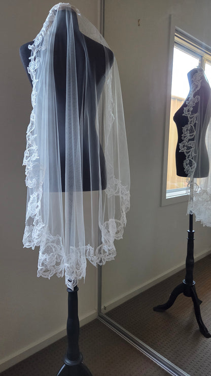 ivory lace wedding veil on a mannequin in front of a mirror.