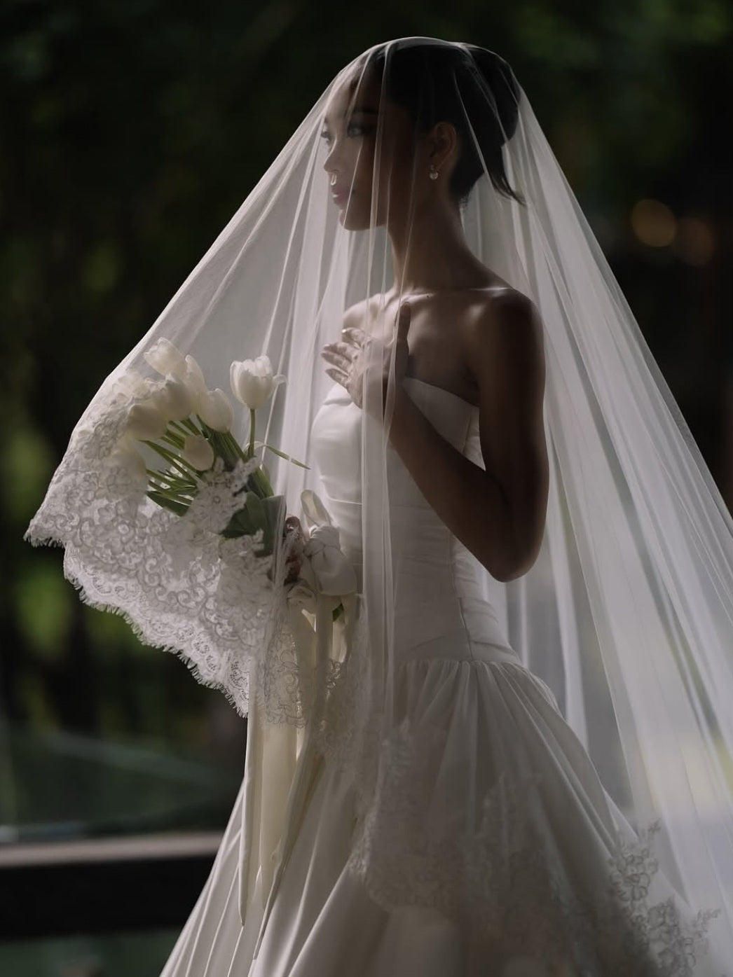 Woman in a white wedding dress with a long veil holding a bouquet.